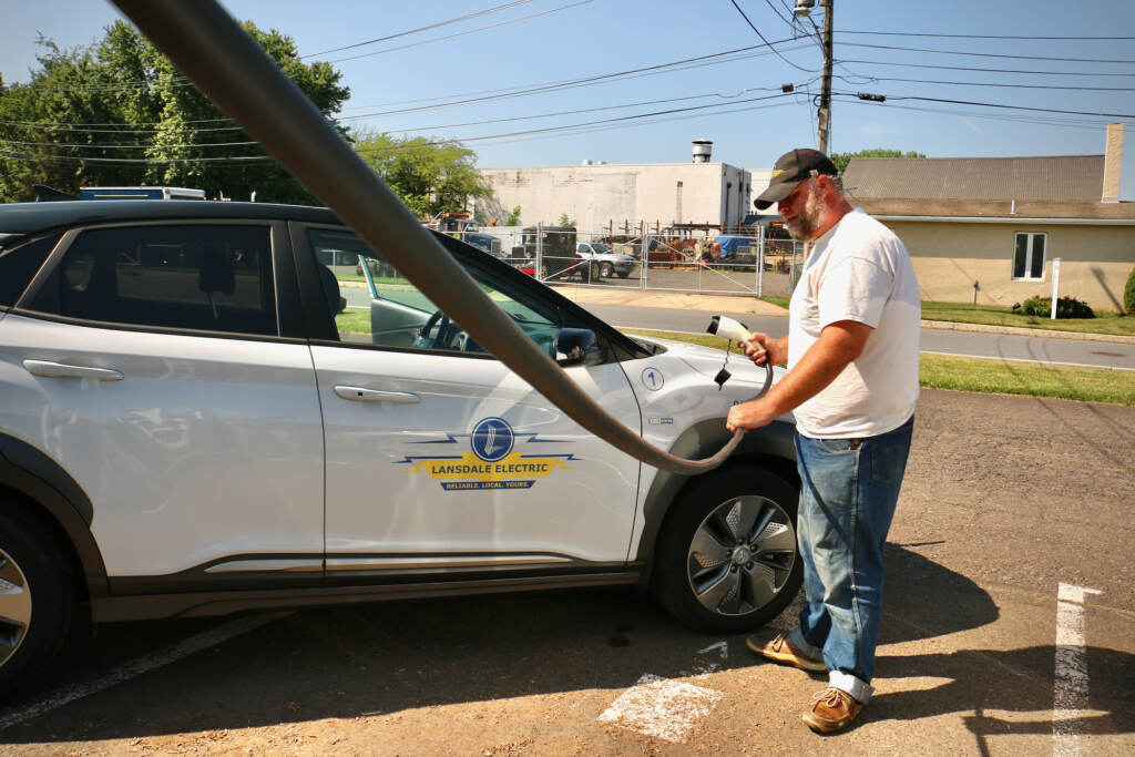 2022 07 01-e lee-andrew krauss-lansdale pa-electric vehicles public charging Andrew Krauss charges an electric vehicle, with the road visible in the background.