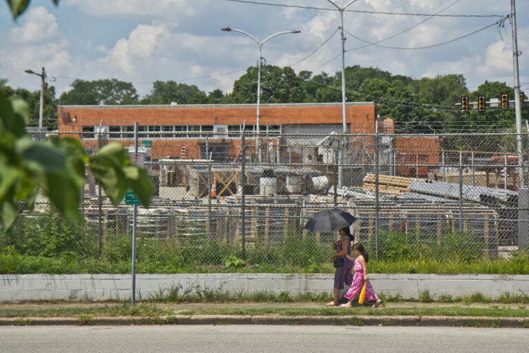 A woman uses an umbrella for protection from the sun in Juniata Park