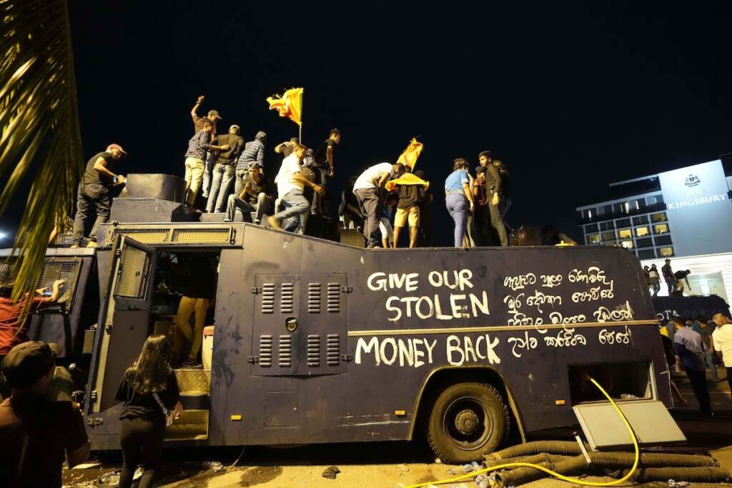 Sri Lanka Protesters stand on a vandalised police water canon truck and shout slogans at the entrance to president's official residence in Colombo, Sri Lanka, Saturday, July 9, 2022. (AP Photo/Eranga Jayawardena)