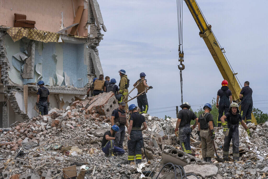 Russia Ukraine War Rescue workers in Ukraine stand on a pile of rubble.
