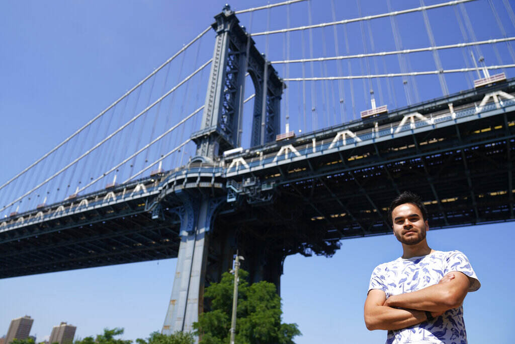 Smarter AI-Cracking the Black Box A person stands with their arms crossed, with a bridge and blue sky visible in the background.