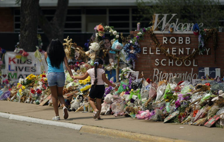 Visitors walk past a makeshift memorial honoring those recently killed at Robb Elementary School, Tuesday, July 12, 2022, in Uvalde, Texas. (AP Photo/Eric Gay)
