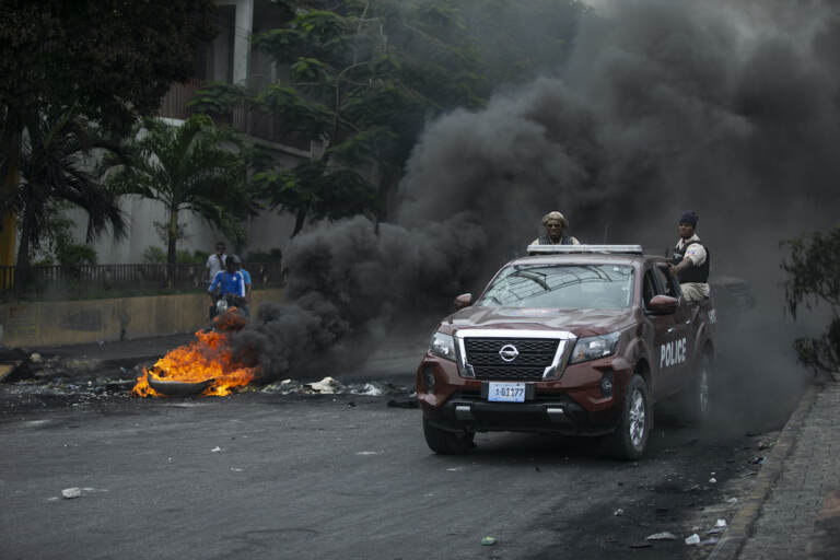 Police drive their car over a barricade set up by taxi drivers to protest fuel shortages in Port-au-Prince, Haiti, Thursday, July 14, 2022. (AP Photo/Odelyn Joseph)
