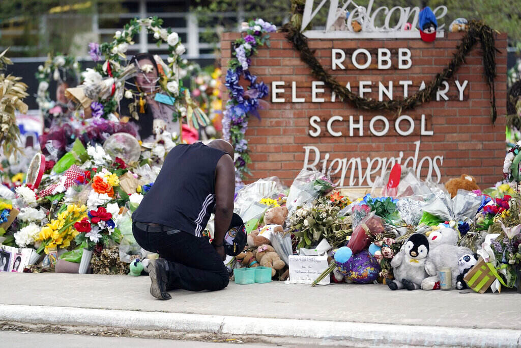 Reggie Daniels A man kneels in front of a memorial surrounding the sign that reads,