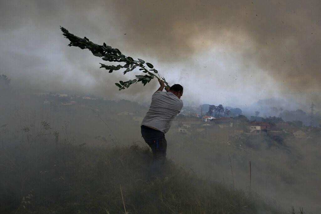 Europe Wildfires Photo Gallery A volunteer uses a tree branch trying to prevent a forest fire from reaching houses in the village of Casal da Quinta, outside Leiria, central Portugal, Tuesday, July 12, 2022. (AP Photo/Joao Henriques)