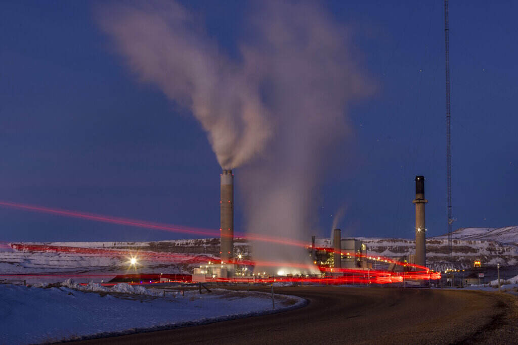 Supreme Court Climate States Smoke rises from a power plant, as the lights glow red in a snowy landscape at night.