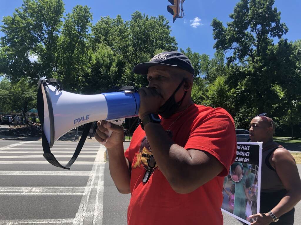 IMG_2310 Jamal Johnson, from Germantown, protests outside Sesame Place on Saturday. Johnson and others aimed to raise awareness about what they say is discriminatory behavior from employees at the Bucks County theme park. (Emily Rizzo/WHYY)