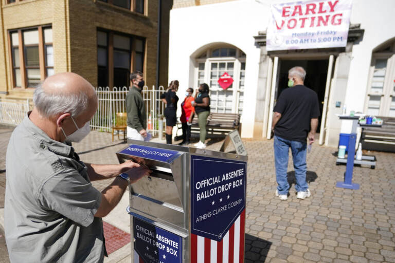 A man puts a ballot in a ballot drop box.