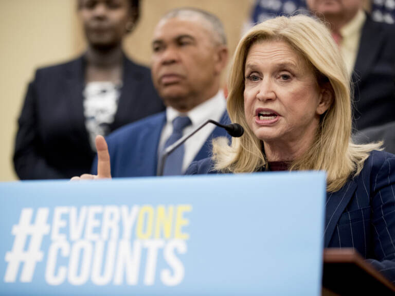 Someone speaks at a podium with a sign reading, 