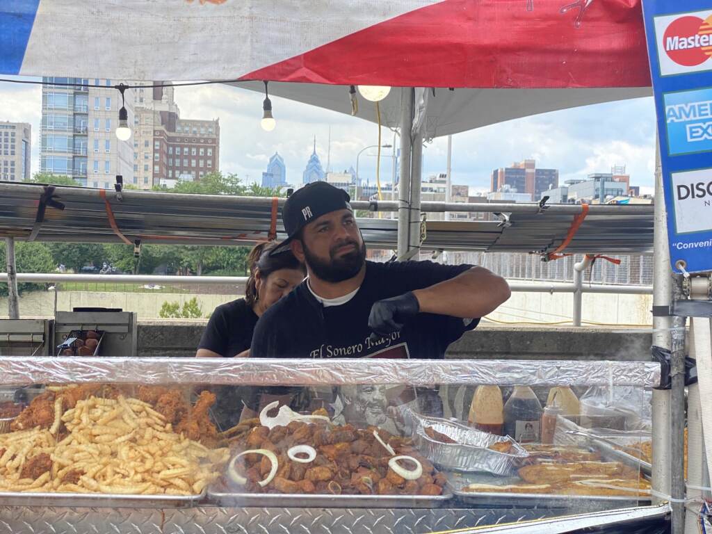 A chef looks over the countertop of his vendor station where he is selling food.