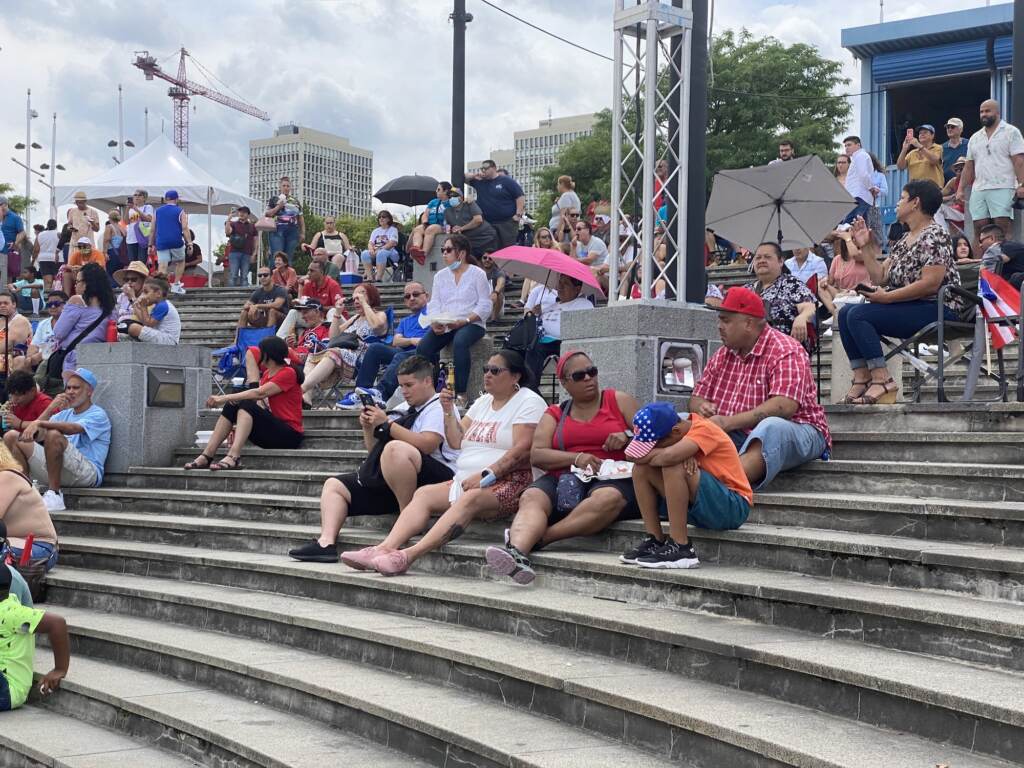 A crowd of people sit together on a large, open staircase.