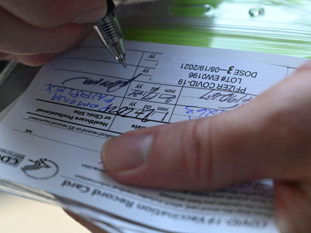 US-HEALTH-VIRUS-VACCINE-BOOSTER A nurse marks a COVID vaccine card with information about a booster dose