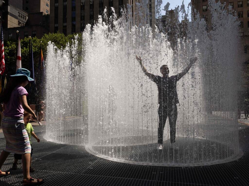 US-WEATHER-HEAT A person holds their arms up in a sprinkler.