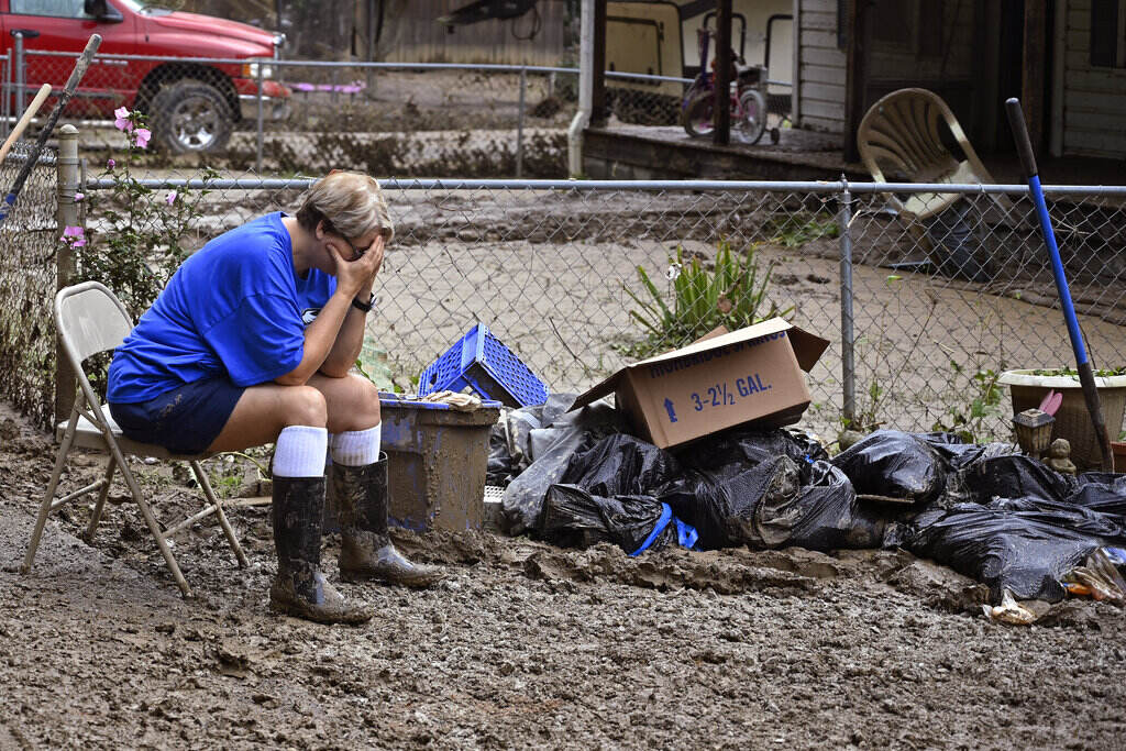 TeresaReynold A woman sits with her head in her hands next to a pile of debris.