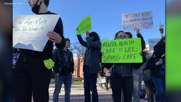People hold signs calling for more mental health support.