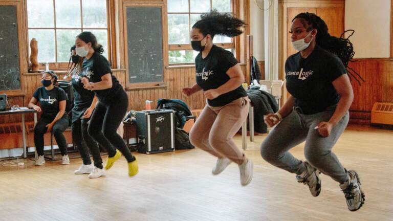 Girls jump in the air in a dance class.