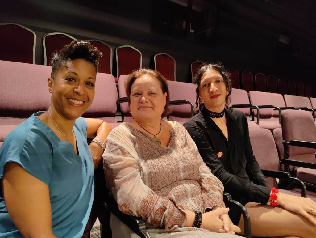 playpenn-reemerges-07-03-22 Three people pose, smiling, in a theater.