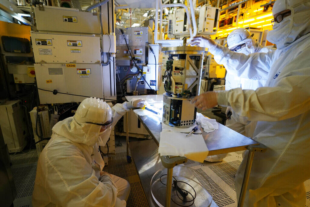 Technicians inspect a piece of equipment during a tour of the Micron Technology automotive chip manufacturing plant Feb. 11, 2022, in Manassas, Va. A bill to boost semiconductor production in the United States is making its way through the Senate is a top priority of the Biden administration. It would add about $79 billion to the deficit over 10 years, mostly as a result of new grants and tax breaks that would subsidize the cost that computer chip manufacturers incur when building or expanding chip plants in the U.S.