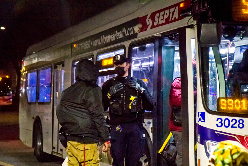 septapolice-bus A police officer stands at the doorway of a bus as someone goes to get on.
