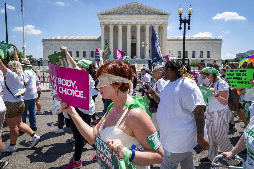 Mahayana Landowne Someone walks with a blindfold over their eyes in protest in Washington, D.C., carrying a sign that reads,