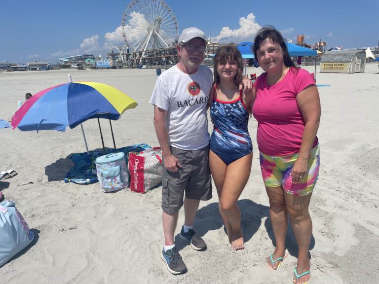 Cheryl Lozada (right) with her husband, Tom, and daughter, Leah, on the beach in Wildwood, N.J. on August 10, 2022. Lozada said she and her family have been vacationing here since Leah was a toddler adding that they were going to come regardless of the cost. (P. Kenneth Burns/WHYY)