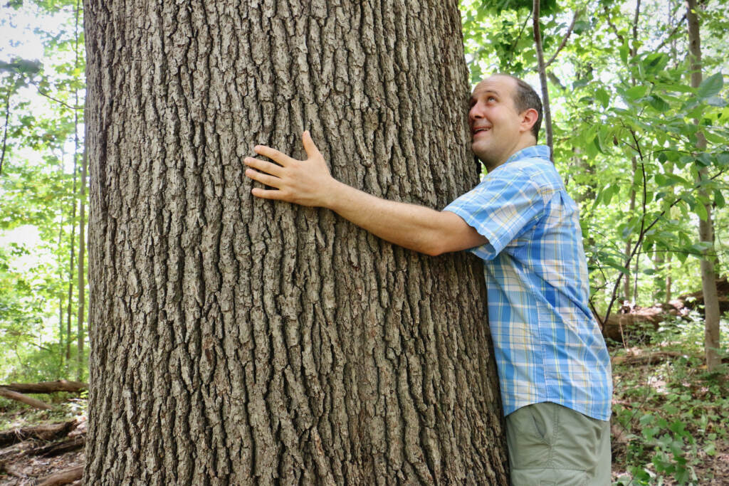 2022 08 11-e lee-bernard brown-philadelphia haddington woods-exploring philly nature tree hug Bernard ''Billy'' Brown hugs a tree in Haddington Woods near Cobbs Creek. Brown is the author of a new guide book, ''Exploring Philly Nature.'' (Emma Lee/WHYY)