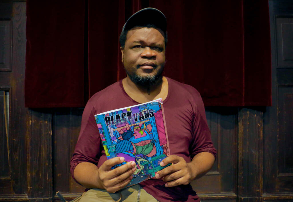 2022 08 15-e lee-alex smith-philadelphia-black gay comic book Alex Smith looks at the camera and holds his comic book in front of him.