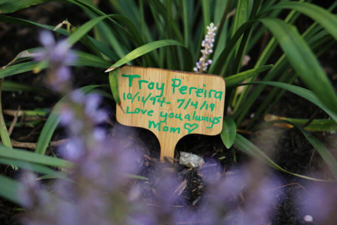 A tiny wooden marker placed in the Philadelphia Overdose Memorial Garden carries a message of love from the mother of Troy Pereira. (Emma Lee/WHYY)