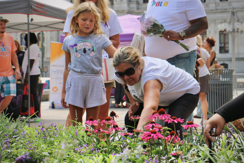 2022 08 31-e lee-stella sniras mary roth-philadelphia thomas paine plaza-overdose memorial garden grand opening Mary Roth is comforted by her granddaughter, Stella Sniras, as she places a marker in the Philadelphia Overdose Memorial Garden for her son, Andrew Roth, who died of an overdose in July 2020.