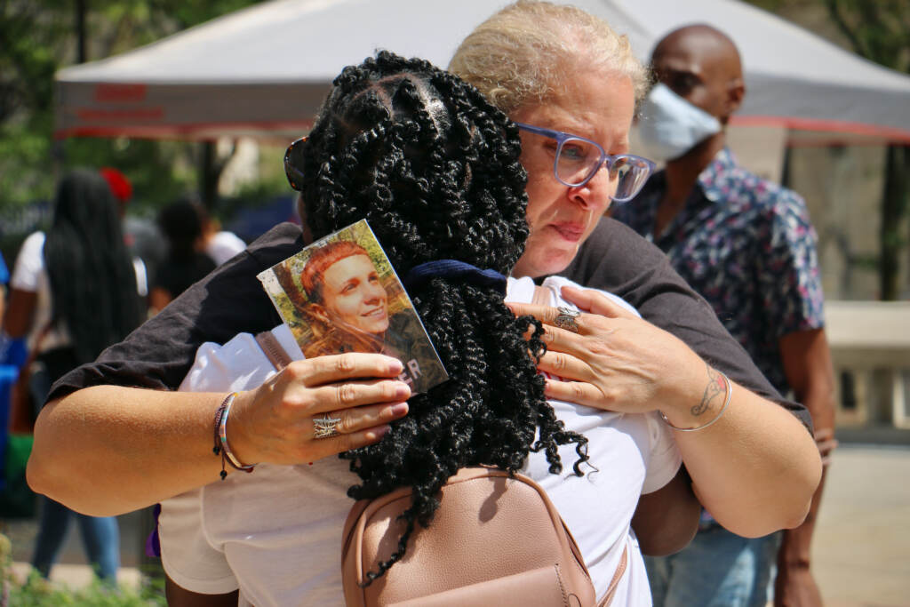 2022 08 31-e lee-terri spina-philadelphia thomas paine plaza-overdose memorial garden grand opening hug Terri Spina shares a tearful hug at the opening ceremony of the Philadelphia Overdose Memorial Garden at Thomas Paine Plaza in 2022. Spina holds a photo of her daughter, Ginamarie Vicent, who died of an overdose at the age of 31. (Emma Lee/WHYY)