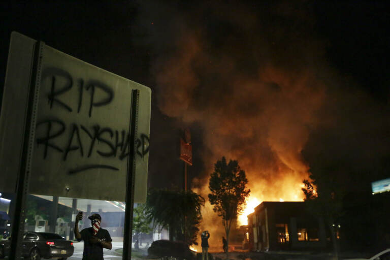 File photo: ''RIP Rayshard'' is spray painted on a street sign as as flames engulf a Wendy's restaurant during protests in Atlanta on Saturday, June 13, 2020. (AP Photo/Brynn Anderson)