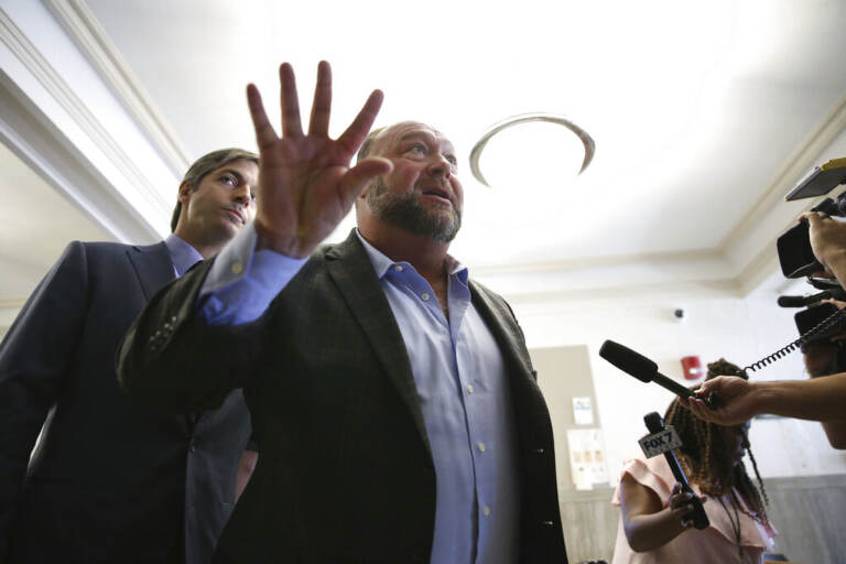 Alex Jones talks to media during a midday break during the trial at the Travis County Courthouse in Austin, Texas, Tuesday, July 26, 2022. An attorney for the parents of one of the children who were killed in the Sandy Hook Elementary School shooting told jurors that Jones repeatedly “lied and attacked the parents of murdered children” when he told his Infowars audience that the 2012 attack was a hoax. (Briana Sanchez/Austin American-Statesman via AP, Pool)