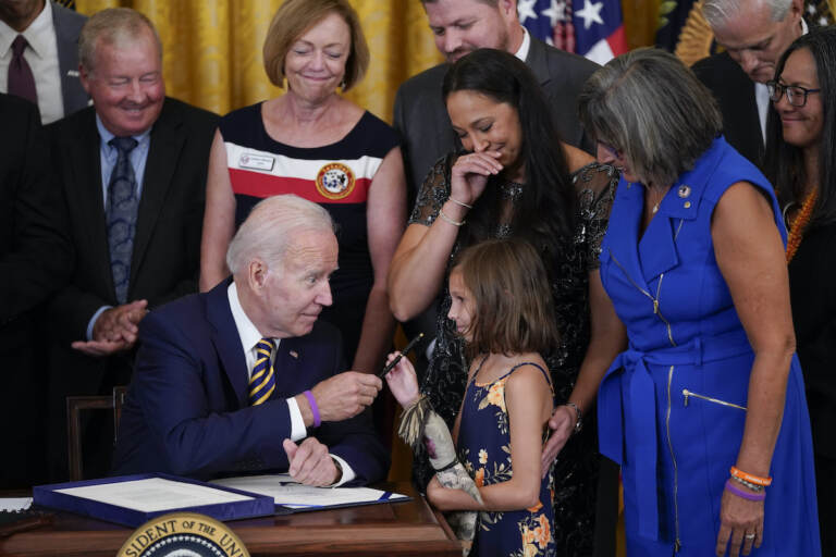 President Joe Biden gives the pen he used to sign the ''PACT Act of 2022'' to Brielle Robinson, daughter of Sgt. 1st Class Heath Robinson, who died of cancer two years ago, during a ceremony in the East Room of the White House, Wednesday, Aug. 10, 2022, in Washington. (AP Photo/Evan Vucci)