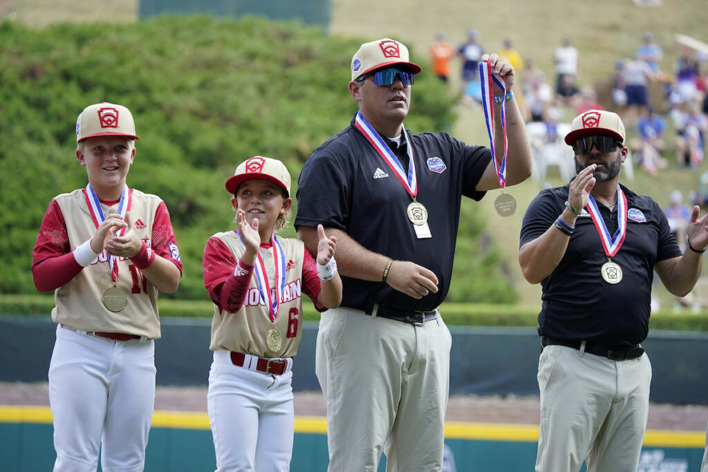 LLWS Tennessee Utah Baseball Jace Oliverson, center, father of Little Leaguer Easton Oliverson who was injured, holds Easton's medal, with another son, Brogan Oliverson (6) at his side, taking Easton's place on the championship team from Santa Clara, Utah before a baseball game against Nolensville, Tenn., at the Little League World Series in South Williamsport, Pa., Friday, Aug. 19, 2022. (AP Photo/Gene J. Puskar)