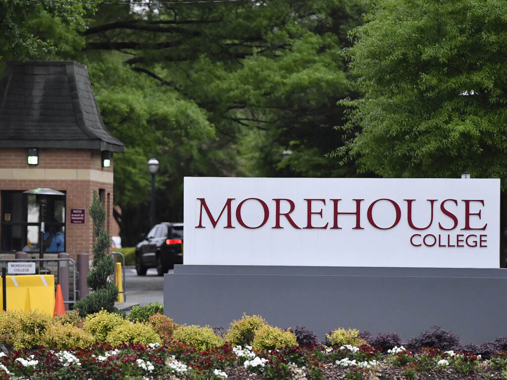 Morehouse College is one of several historically Black colleges and universities seeing a surge in applications and enrollments in recent years. A sign reads Morehouse College, with green trees in the background.