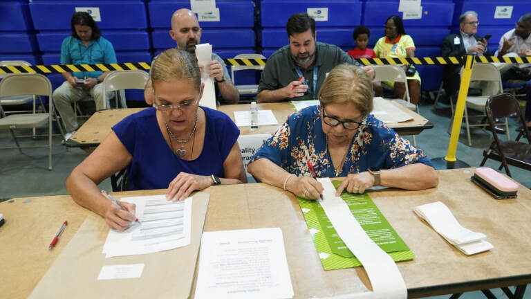Two election employees check the tabulations made by voting equipment.