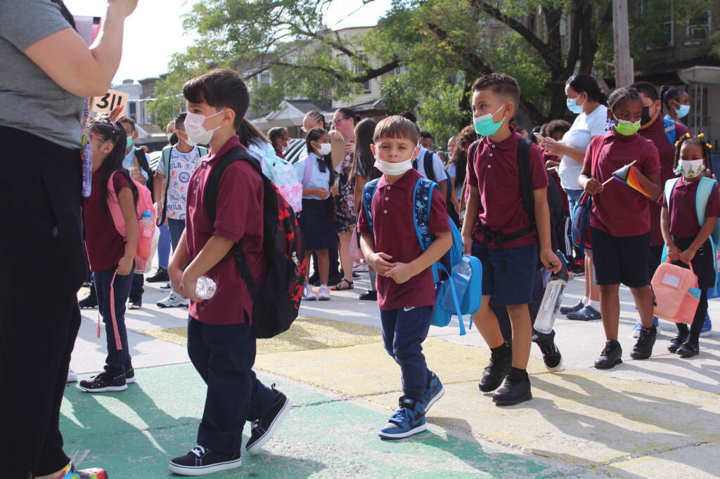 first-day-school-philly-2022-1 A line of young students wearing red polo shirts stand before a teacher.