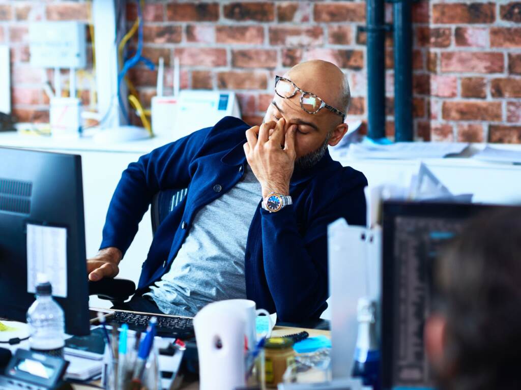 Tired man sitting at desk in modern office