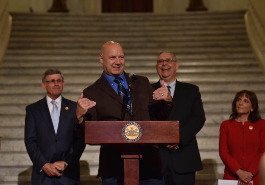 mastriano-gop-pa-elections Mastriano speaks and gestures at a podium. Other men stand in the background.