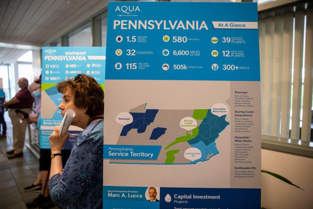 pa-climate-bill-back-door-privatization A sign shows a map of Pennsylvania with a person standing behind it.