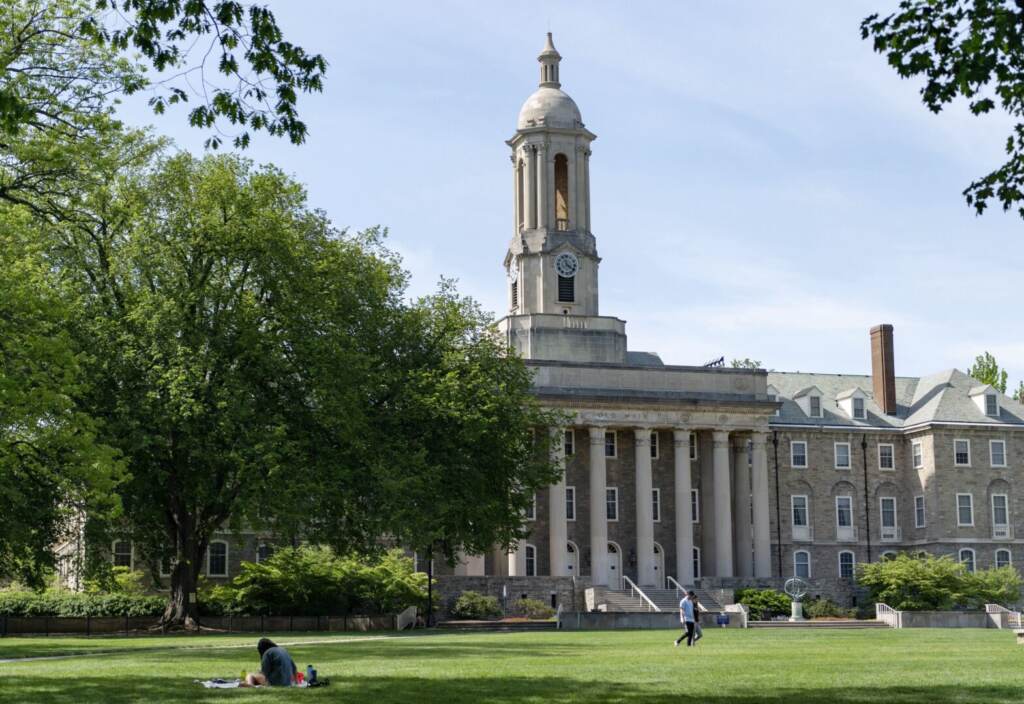 People walk across Old Main lawn on the Penn State campus
