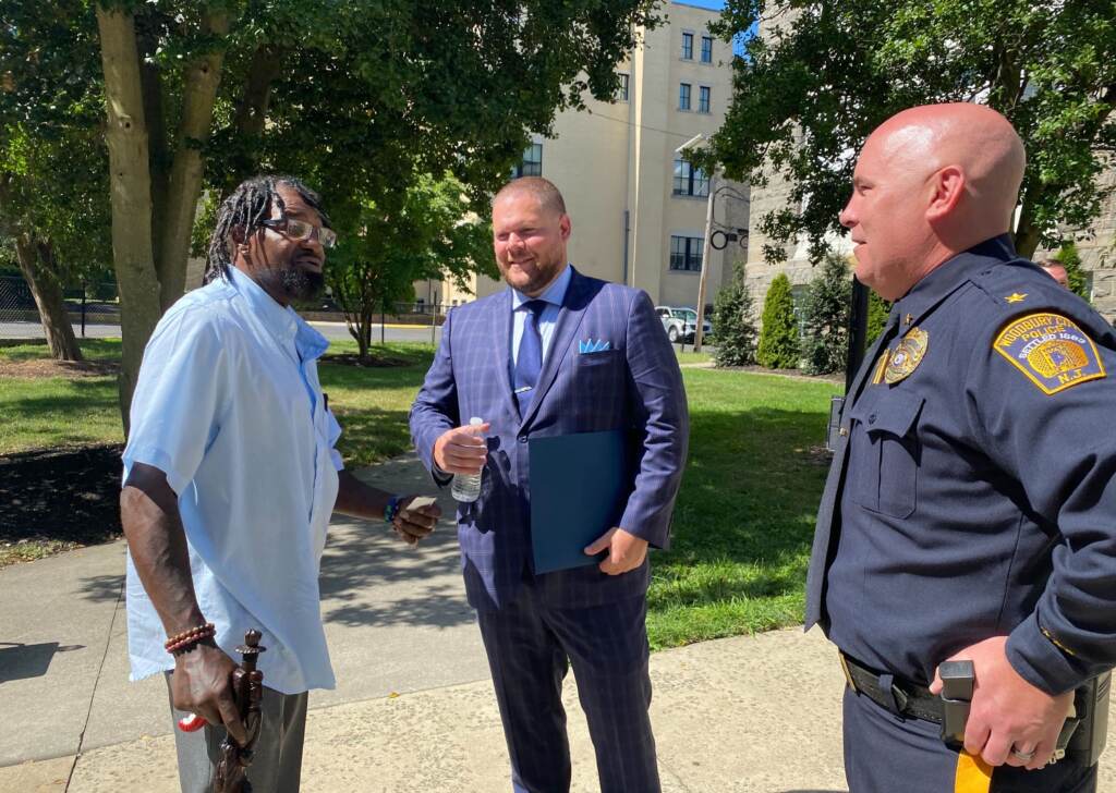 rodney-dean-soodbury-junior-senior-high-school Rodney Dean (left) speaks with Woodbury Junior-Senior High School resource officer Ryan Alcott (middle) and Woodbury Police Chief Thomas Ryan (right) at a press conference announcing a new law requiring New Jersey schools to implement school threat assessment teams. (Tennyson Donyéa / WHYY)