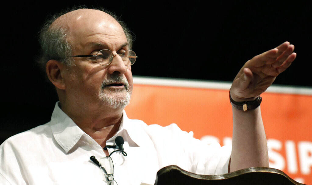 Salman Rushdie Salman Rushdie gestures as he speaks at a podium.