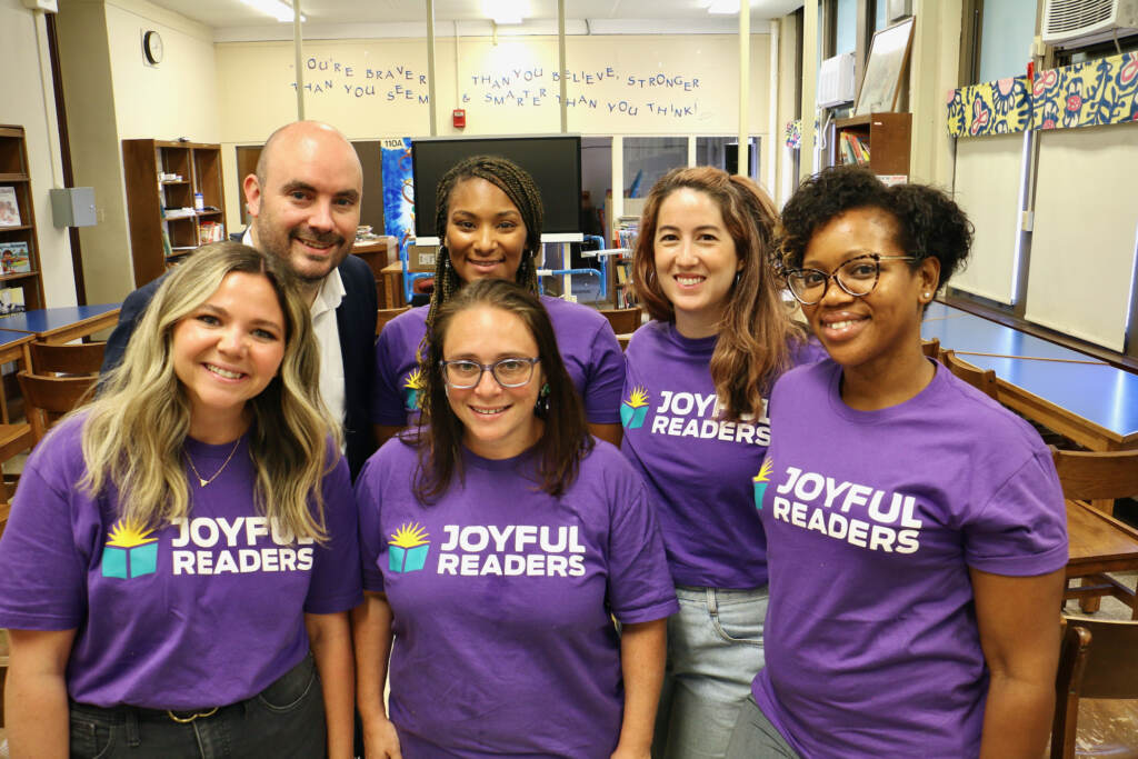 A group of people pose in front of a classroom.