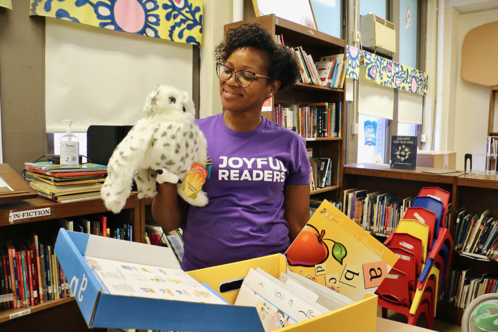 2022 08 25-e lee-tutors-philly-reading-3 A woman in a purple shirt holds a stuffed owl in a classroom.