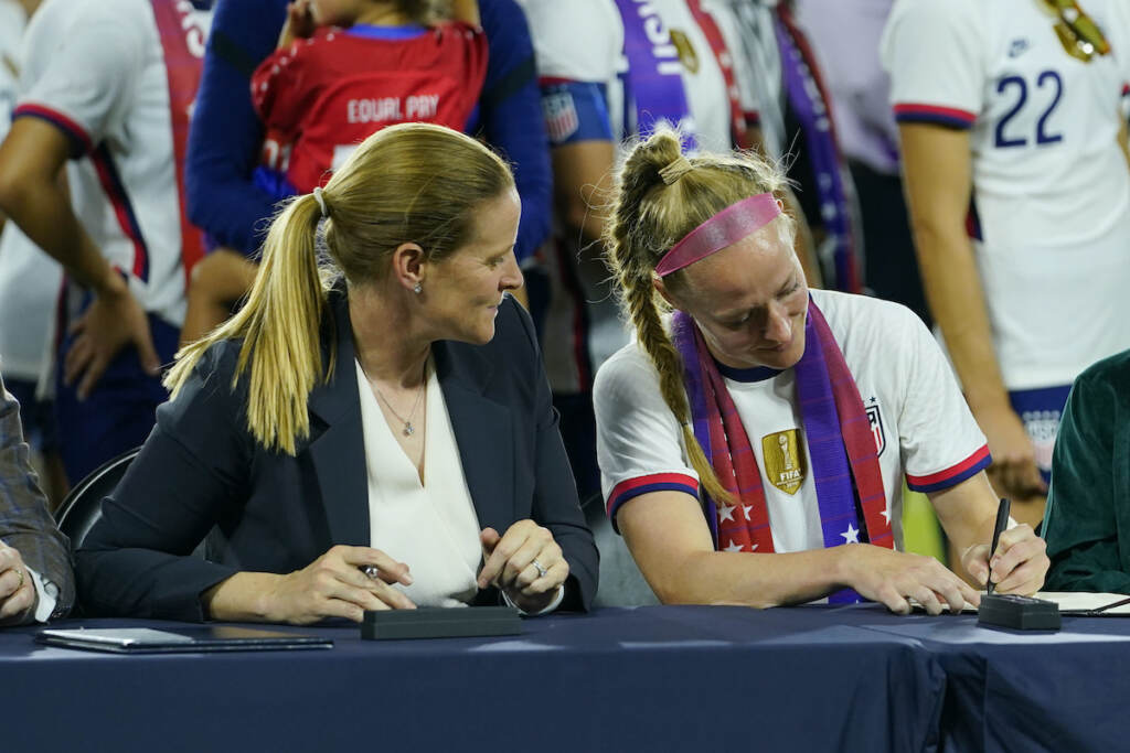 Nigeria US Soccer Cindy Parlow Cone, left, president of the U.S. Soccer Federation, looks on as United States' Becky Sauerbrunn signs a new collective bargaining agreement as part of an event in which with the federation, U.S. Women's National Team Players Association and the U.S. National Soccer Team Players Association signed new collective bargaining agreements following the women's match against Nigeria at Audi Field, Tuesday, Sept. 6, 2022, in Washington. The U.S. won 2-1. (AP Photo/Julio Cortez)
