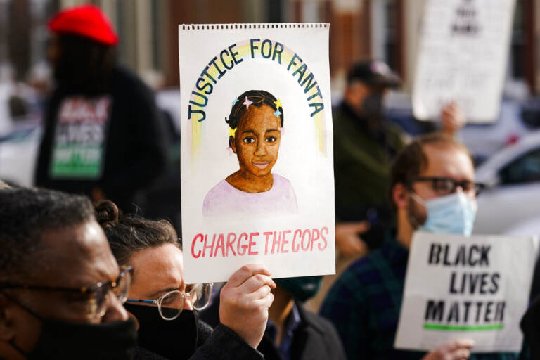 A person holds a sign that reads 