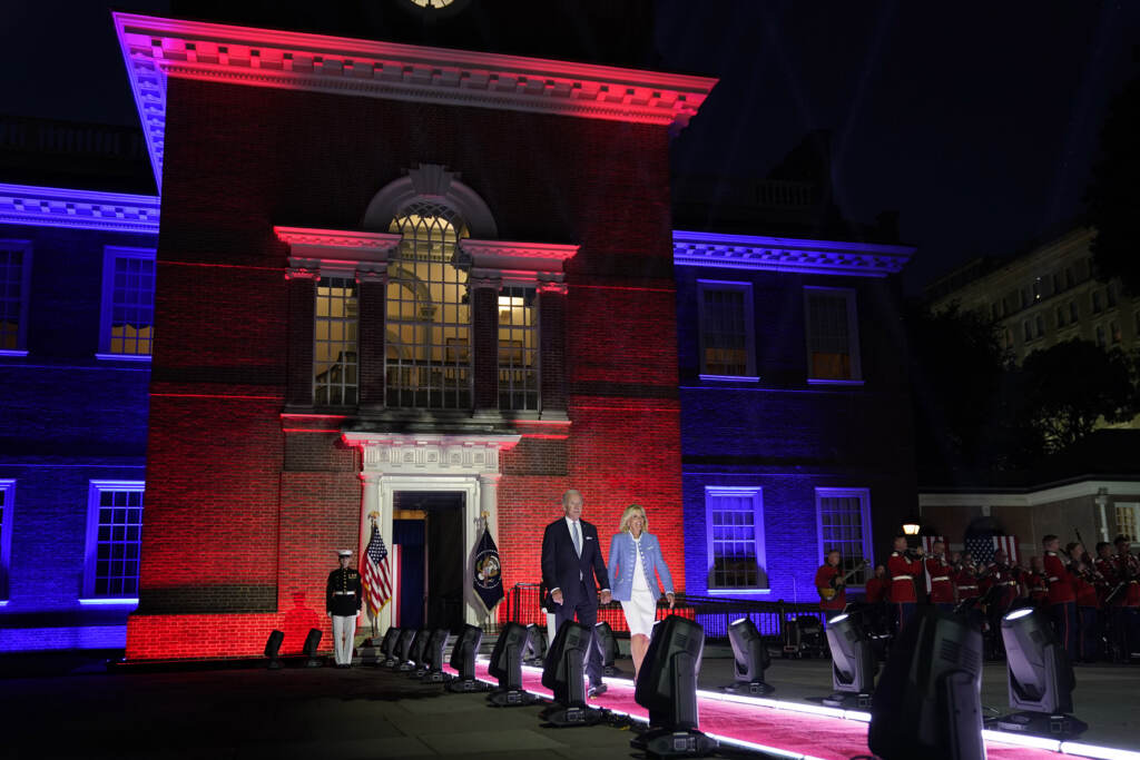 Joe Biden President Biden and First Lady Jill Biden walk out from Independence Hall lit with red and blue lights.