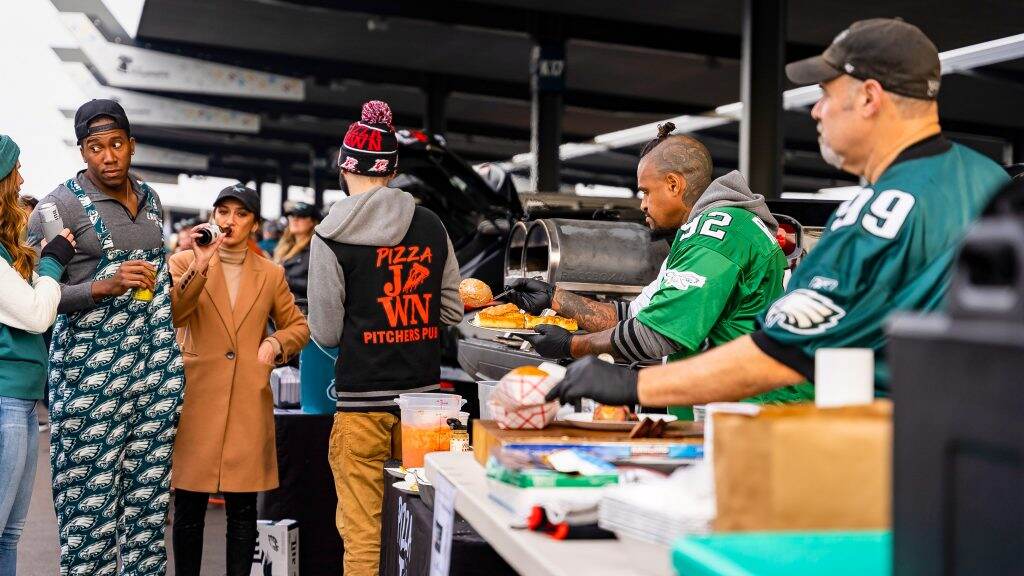 eaglestailgating-pizzajawn-davelee-01-1024×576 Dave Lee of Pizza Jawn (center right, with serving ladle) brings pizza ovens to his Eagles tailgate, and shares food with dozens of others. (Daviston Jeffers)