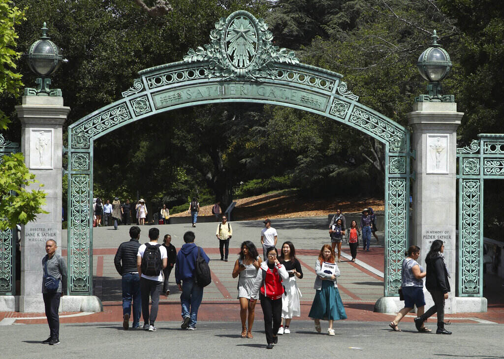 Student Loans States Students walk through a green arch on a college campus.